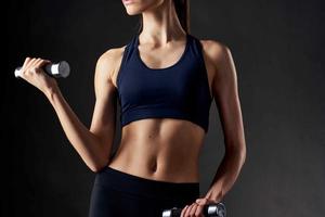 des sports figure de une femme avec haltères dans sa mains bordé foncé Contexte photo