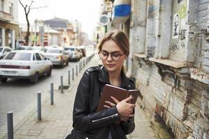 une femme des promenades vers le bas le rue près un vieux bâtiment dans une cuir veste modèle photo