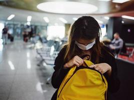 une passager à le aéroport une femme à la recherche dans une Jaune sac à dos photo