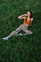 une femme mensonges sur Frais printemps vert herbe dans une parc sans pour autant les moustiques ou tiques et jouit relaxant tandis que en train de regarder le le coucher du soleil. le concept de sûr Extérieur des loisirs photo