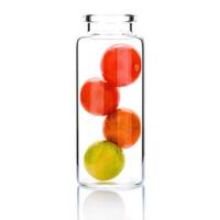 soins de la peau faits maison avec des tomates cerises dans une bouteille en verre isolé sur fond blanc. photo