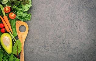 aliments sains et concept de cuisine avec une spatule en bois et légumes sur fond de pierre sombre. photo