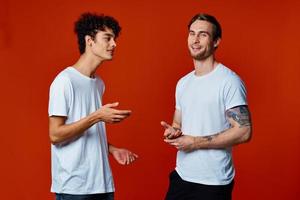 deux de bonne humeur copains dans blanc t-shirts la communication isolé Contexte amusement photo