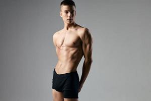 sexy athlète dans noir short sur une gris Contexte bodybuilder biceps modèle copie espace photo