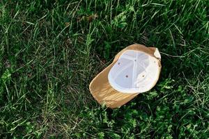 une Jaune des sports casquette mensonges à l'envers vers le bas sur le vert herbe. printemps Extérieur des sports Jeux photo