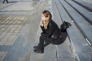 une femme dans une cuir veste est assis sur le escaliers près le théâtre sur le rue modèle photo