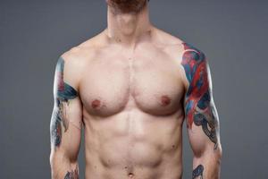 sportif homme avec pompé en haut abdos tatouages sur le sien bras gris Contexte muscles photo