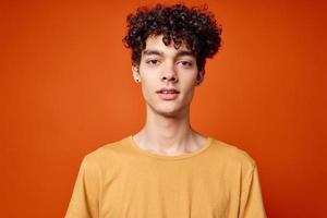 gars avec frisé cheveux dans Jaune T-shirt tondu vue dans isolé Contexte photo