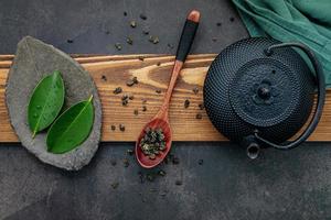 Théière en fonte noire avec tisane mis en place sur un fond de pierre sombre photo