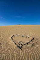cœur symbole de l'amour arrangé de gris pierre sur d'or le sable sur une d'or dune photo