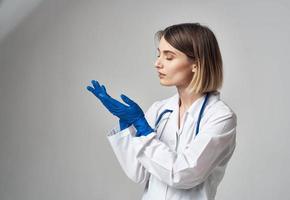 portrait de une infirmière dans gants et une médical robe sur une lumière Contexte photo
