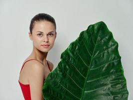 femme dans une rouge maillot de bain attrayant Regardez vert feuille lumière Contexte photo