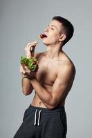 athlétique gars avec nu épaules en mangeant santé énergie faire des exercices photo