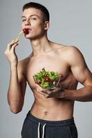 sportif Beau homme avec assiette de salade en bonne santé nourriture faire des exercices isolé Contexte photo