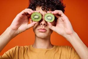 de bonne humeur homme avec frisé cheveux kiwi fruit amusement rouge Contexte photo