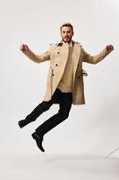 Beau homme dans beige manteau l'automne style sauter studio lumière Contexte photo