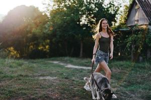 femme et sa rauque chien Heureusement fonctionnement par le herbe dans la nature dans le parc sourire avec les dents tomber marcher avec animal de compagnie, en voyageant avec une chien ami photo