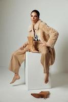 jolie brunette dans une beige fourrure manteau l'automne style mode pieds nus photo