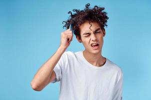 Beau gars avec frisé cheveux sur une bleu Contexte portrait fermer emmêlé boucles photo