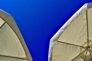 astucieux Contexte avec parapluies contre le toile de fond de une bleu sans nuages ciel sur une chaud été journée à le plage photo