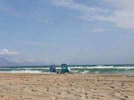 l bord de mer paysage avec deux Soleil chaises longues sur le plage sur le rivages de le turquoise mer sur une chaud été journée photo