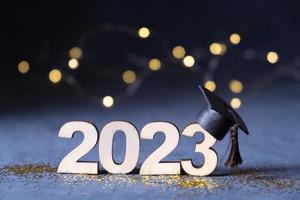 classe de 2023 concept. en bois nombre 2023 avec diplômé chapeau sur foncé Contexte avec bokeh photo