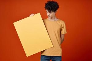 gars avec frisé cheveux en portant un île dans le sien mains La publicité photo