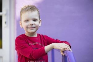 six année vieux garçon. primaire école étudiant. enfant d'âge préscolaire. enfant sur une violet Contexte. peu blond garçon sourit. photo