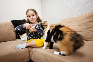 peu fille alimentation le chat avec yaourt de une cuillère à maison. photo