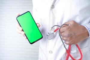 main du médecin tenant stéthoscope et téléphone intelligent avec écran vert