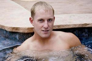 une Beau Jeune homme pose dans le jacuzzi. photo