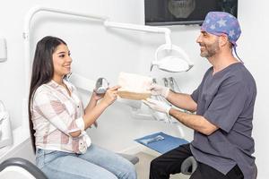 souriant hispanique Masculin dentiste donnant ordonnance à femelle patient photo