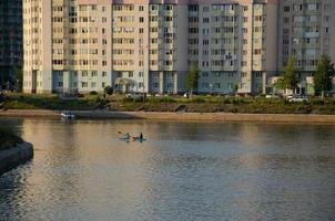 à le coucher du soleil dans le ville sur le rivière entre grand Maisons gens se détendre nager par bateau photo