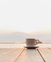 tasse de café sur en bois plate-forme plus de lever du soleil avec rivière Montagne dans Contexte. photo