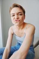 Jeune femme avec court la Coupe de cheveux cheveux ayant amusement à Accueil sur le canapé sourire et bonheur, vacances à maison, Naturel posant sans pour autant filtres, gratuit copie espace photo