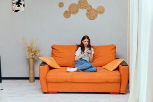 femme avec longue cheveux est séance sur le canapé avec une Téléphone les technologies photo