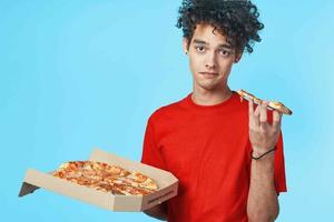 marrant frisé gars dans une rouge T-shirt Pizza livraison vite nourriture casse-croûte photo