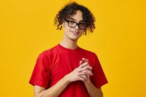 marrant mignonne myope Jeune étudiant homme dans rouge T-shirt lunettes posant isolé sur plus de Jaune studio Contexte. le meilleur offre avec gratuit endroit pour publicité. éducation Université concept photo