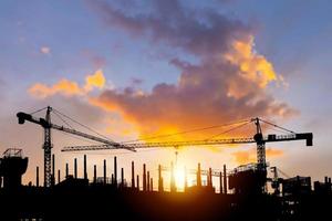 silhouettes de bâtiment construction site et construction grues avec le coucher du soleil Contexte photo