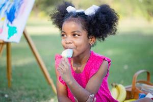 mignonne peu fille jouer dans le jardin, jolie bébé fille enfant en mangeant la glace crème, enfant fille en jouant en plein air photo