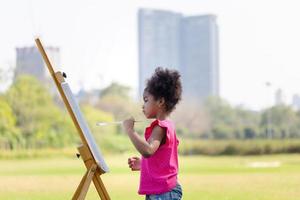 enfant fille La peinture sur Toile dans le jardin, content enfant fille dessin une image en plein air photo