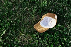 une Jaune des sports casquette mensonges à l'envers vers le bas sur le vert herbe. printemps Extérieur des sports Jeux photo