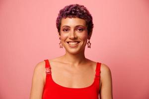 mode portrait de une femme avec une court la Coupe de cheveux de violet Couleur et une sourire avec les dents dans une rouge Haut sur une rose Contexte bonheur photo