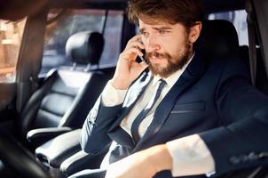 barbu homme dans une costume dans une voiture une voyage à travail la communication par téléphone photo