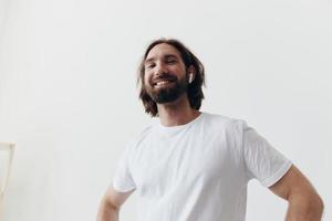 content homme écoute à la musique et souriant dans une blanc T-shirt sur une blanc Contexte content photo