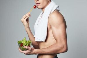 homme avec pompé en haut corps serviette sur épaules assiette avec salade en bonne santé nourriture photo