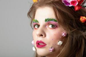 portrait de une magnifique fille avec Créatif se maquiller. été fille. le visage de une luxueux modèle dans fleurs. Naturel produits de beauté concept. photo