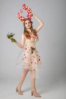 Conte de fée fille modèle avec floral cornes bouquet sur une studio Contexte. maléfique. printemps ou été beauté. femme dans le image de une fleur. forêt femme. photo