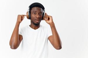 homme de africain apparence dans blanc T-shirt avec écouteurs écoute à la musique photo