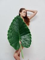 femme avec une nu corps une grand vert feuille dans sa mains lumière Contexte photo